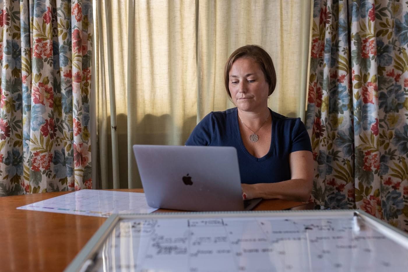 Clare working at her laptop, surrounded by printed calendars